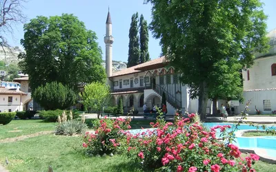 Wielki Meczet Chański z minaretem i ogród z kwitnącymi różami w Pałacu Chanów w Bakczysaraju