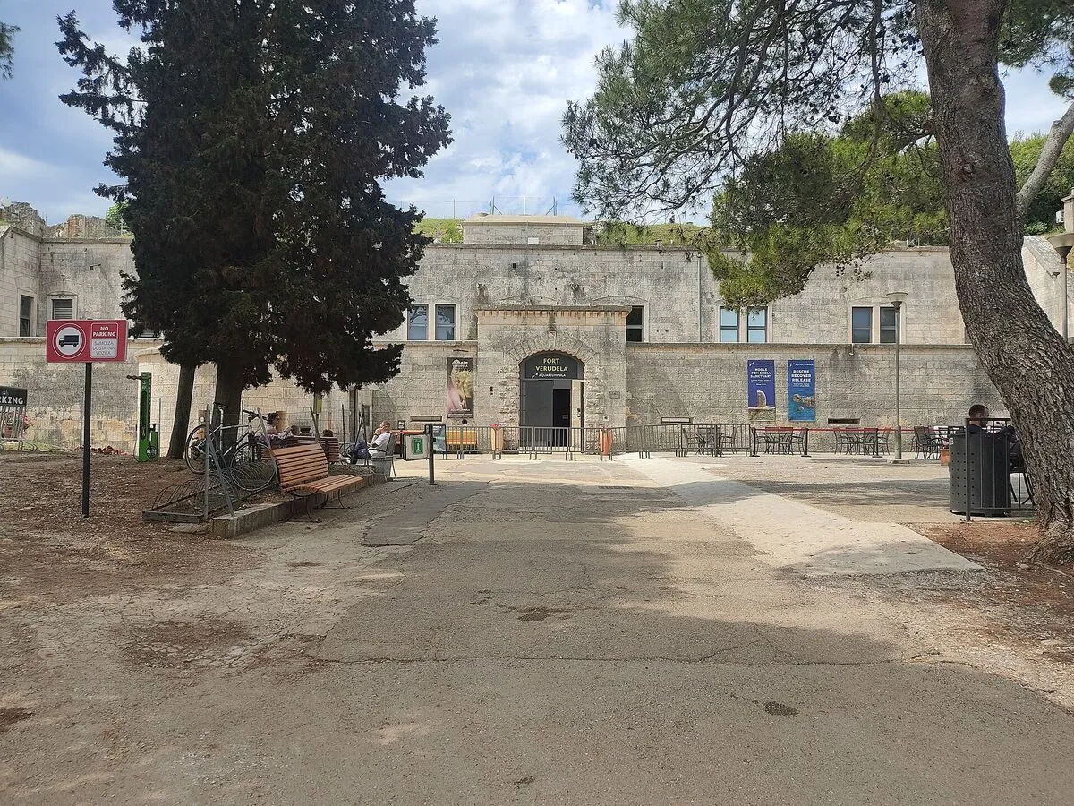 Wejście do Aquarium Pula w austro-węgierskim forcie Verudela, z kamienną fasadą i plakatami akwarium