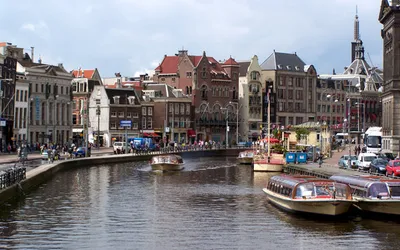 Kanał w centrum Amsterdamu z łodziami wycieczkowymi i ceglanymi kamienicami