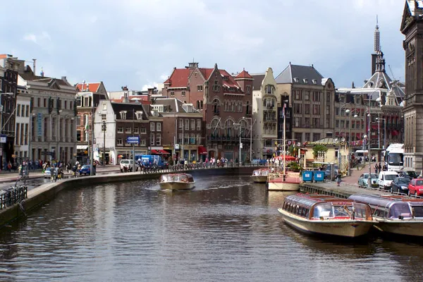 Kanał w centrum Amsterdamu z łodziami wycieczkowymi i ceglanymi kamienicami
