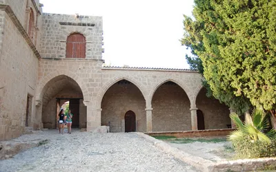 Kamienny dziedziniec klasztoru Ayia Napa z arkadowymi krużgankami i cyprysem