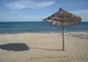 Parasol z suszonej trzciny na pustej, piaszczystej plaży w Hammamecie, w tle turkusowe morze
