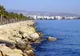 Kamienny falochron, palmy i wysokie budynki nad wybrzeżem Limassol