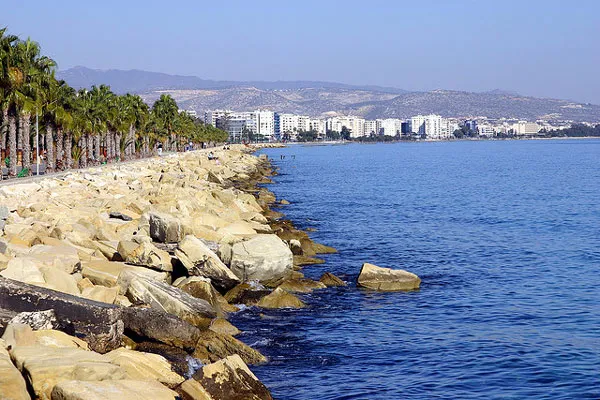 Kamienny falochron, palmy i wysokie budynki nad wybrzeżem Limassol