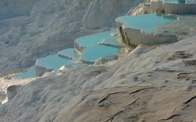 Białe trawertynowe tarasy Pamukkale z błękitną wodą