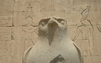 Granitowy posąg sokoła Horusa przed ścianą z płaskorzeźbami w świątyni w Edfu