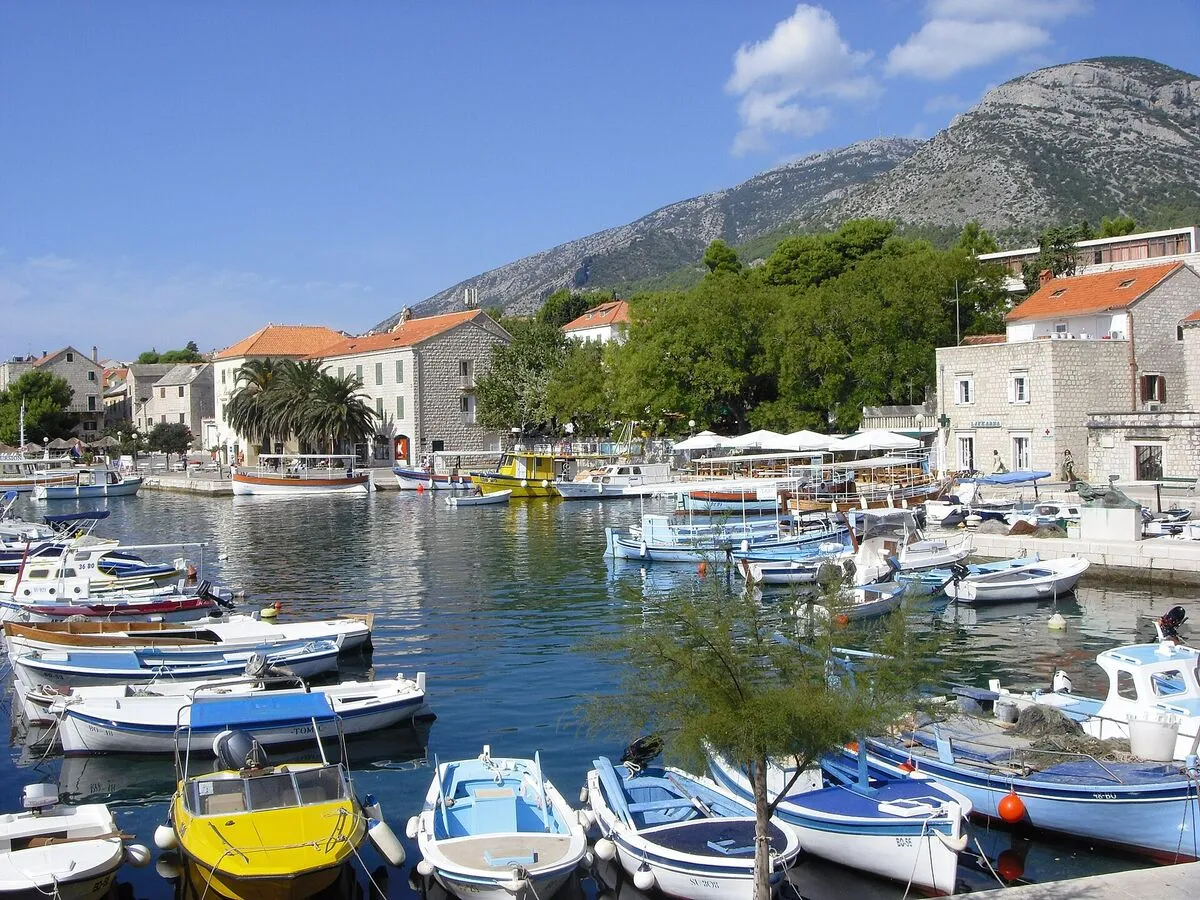Port w Bolu z łódkami, kamiennymi domami i górami w tle