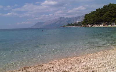 Jasna żwirowa plaża w Breli z przejrzystą wodą i masywem Biokovo w tle