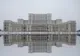 Monumentalna fasada Pałacu Parlamentu w Bukareszcie odbita w tafli wody zimą