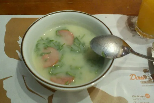 Miska zielonej zupy caldo verde z plastrami kiełbasy