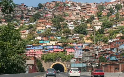 Kolorowe domy na zboczu wzgórza nad autostradą i tunelem w Caracas