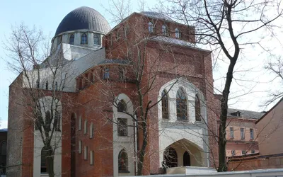 Ceglana fasada Synagogi Chóralnej w Charkowie z ostrołukowymi oknami i ciemną kopułą, przed nią bezlistne drzewa