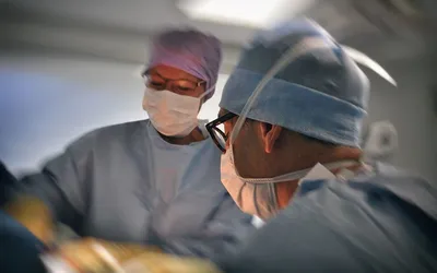 Chirurdzy w czepkach i maseczkach podczas operacji na sali operacyjnej