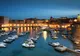 Stary port w Dubrowniku nocą, z oświetlonymi murami miasta