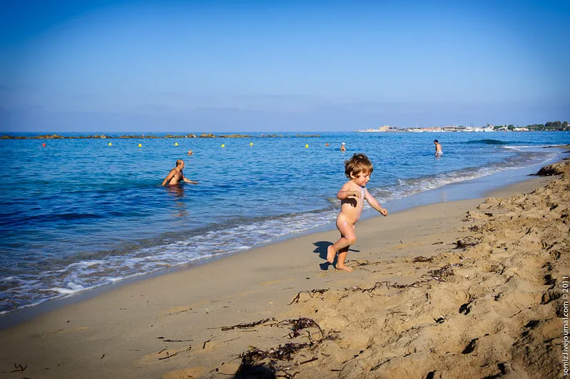 Małe dziecko biegnie przy brzegu piaszczystej plaży