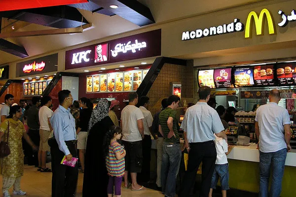 Klienci w codziennych, zakrywających ramiona strojach w kolejce do barów w strefie gastronomicznej Dubai Mall
