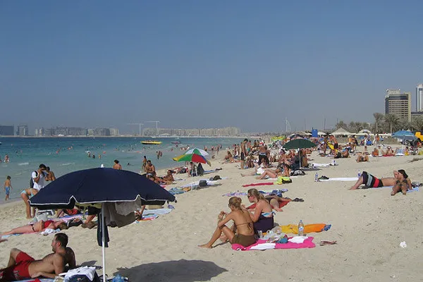 Turyści w strojach kąpielowych na zatłoczonej publicznej plaży w Dubaju