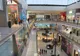 Wielopoziomowe wnętrze Dubai Mall z przeszklonymi balustradami, sklepami i palmami na parterze
