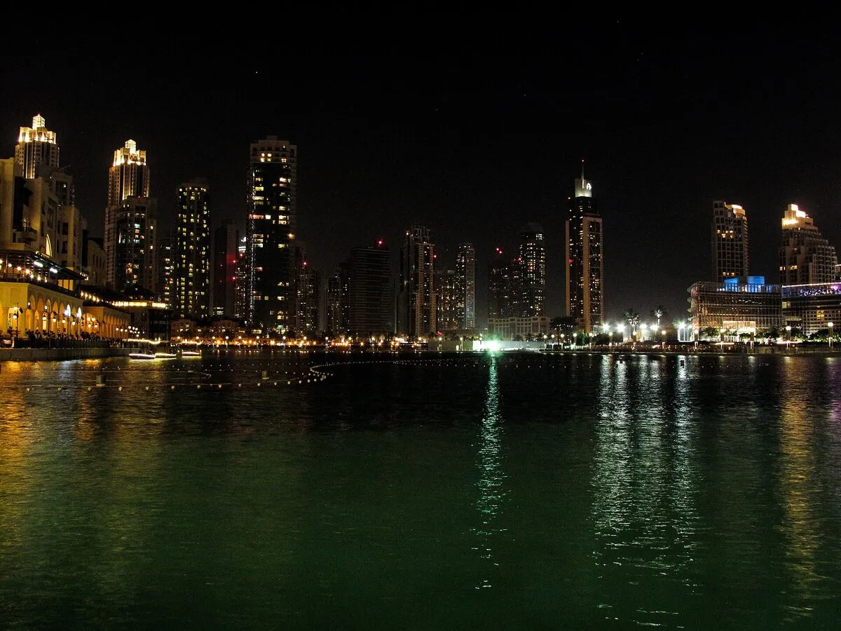 Nocna panorama wieżowców Downtown Dubai odbijających się w wodzie jeziora