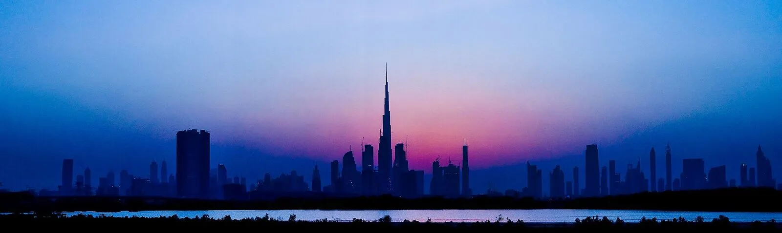 Sylwetki wieżowców Dubaju z Burdż Chalifa na tle wieczornego nieba