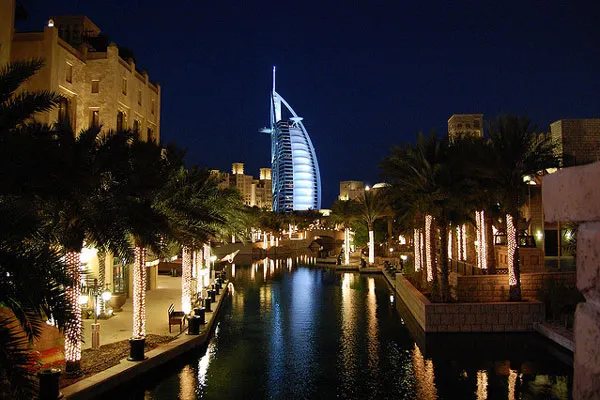 Souk Madinat Jumeirah nocą, w oddali podświetlony hotel Burj Al Arab