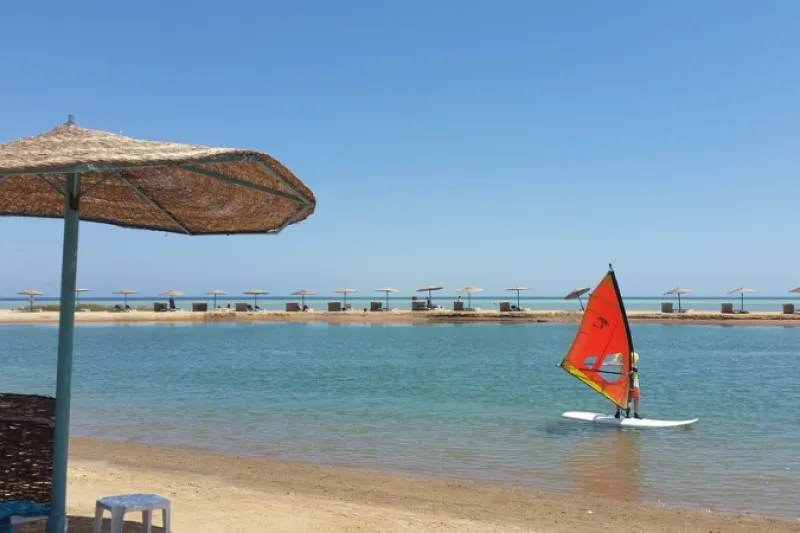 Plaża z parasolami i windsurfer na lagunie w Al-Dżunie