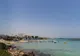 Piaszczysta plaża z parasolami w zatoce Fig Tree Bay w Protaras, w tle hotele i turkusowe morze z łodziami