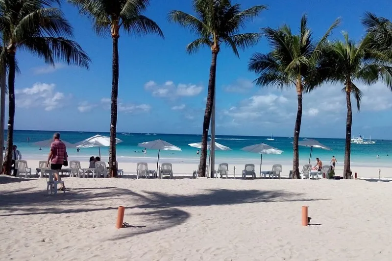 Biała plaża z palmami, leżakami i parasolami na wyspie Boracay