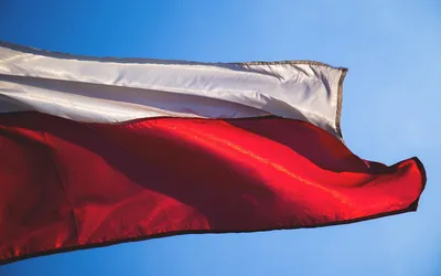 Biało-czerwona flaga Polski łopocząca na tle błękitnego nieba