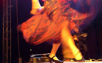 Wirująca spódnica tancerki flamenco na scenie, w tle gitarzysta