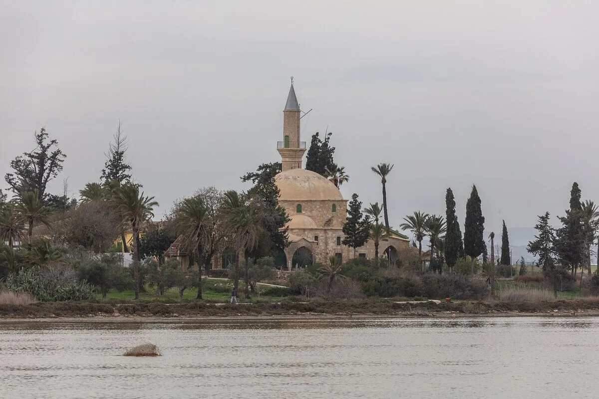 Meczet Hala Sultan Tekke z minaretem wśród palm i cyprysów nad brzegiem Słonego Jeziora
