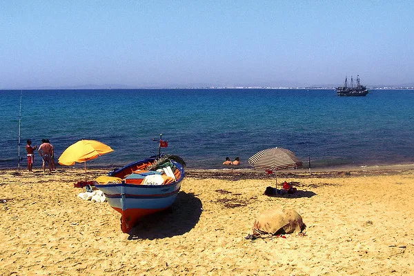 Kolorowa łódź rybacka i parasole na plaży w Hammamecie