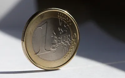 Moneta 1 euro stojąca na krawędzi w smudze słońca