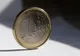 Moneta 1 euro stojąca na krawędzi w smudze słońca