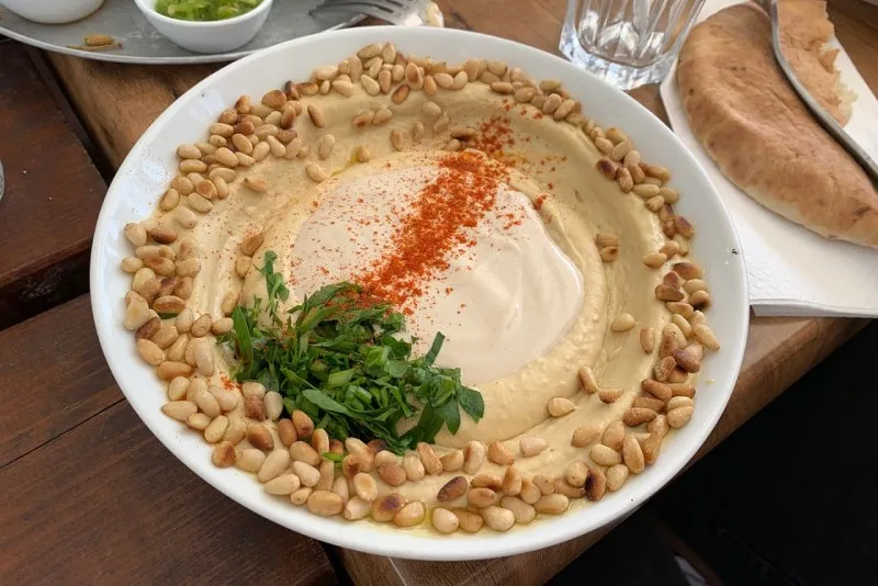 Talerz hummusu z tahini, orzeszkami piniowymi, papryką i natką pietruszki