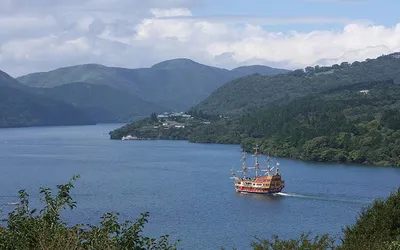 Stylizowany na żaglowiec statek wycieczkowy na jeziorze Ashi otoczonym zalesionymi górami Hakone