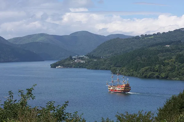Statek wycieczkowy na jeziorze Ashi otoczonym zalesionymi górami Hakone