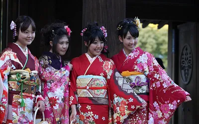 Cztery młode Japonki w czerwonych kimonach furisode z szerokimi pasami obi