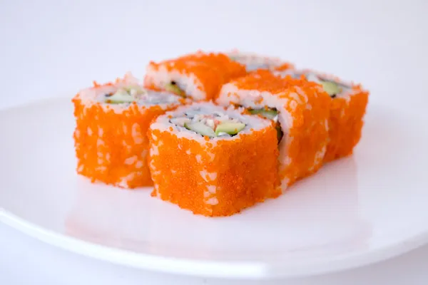Roladki sushi obsypane pomarańczową ikrą na białym talerzu
