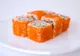 Roladki sushi obsypane pomarańczową ikrą na białym talerzu