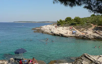 Skalista plaża i turkusowa zatoka na przylądku Kamenjak