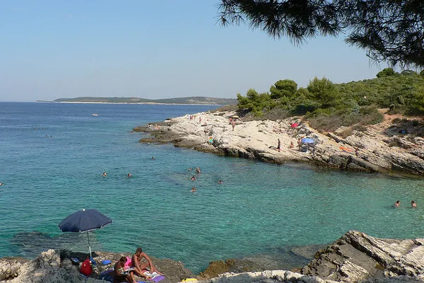 Skalista plaża i turkusowa zatoka na przylądku Kamenjak