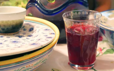 Szklanka ciemnoczerwonego naparu z hibiskusa na stole obok ceramicznych naczyń