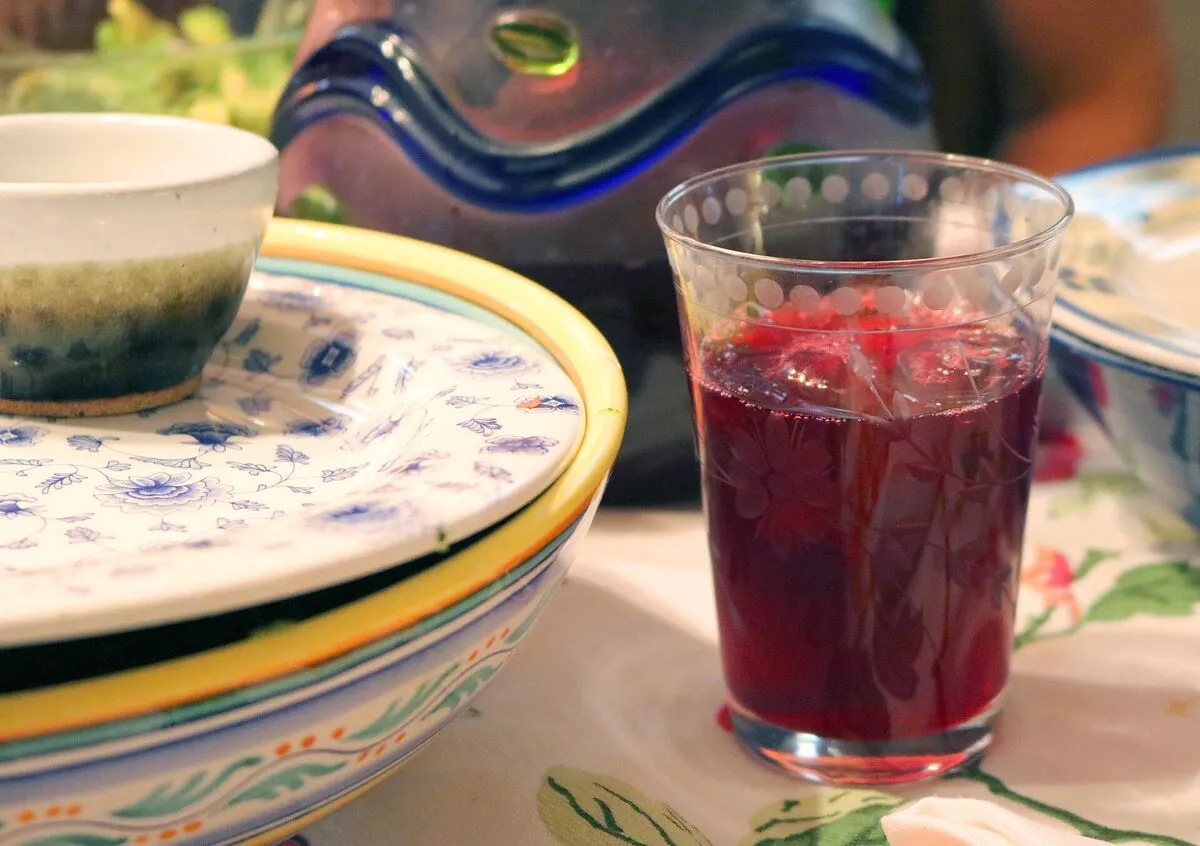 Szklanka ciemnoczerwonego naparu z hibiskusa na stole obok ceramicznych naczyń