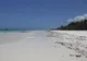 Biały piasek i turkusowa woda na plaży Diani, po prawej palmy kokosowe