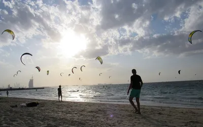 Latawce kitesurferów nad plażą Kite Beach w Dubaju, w tle hotel Burdż al-Arab