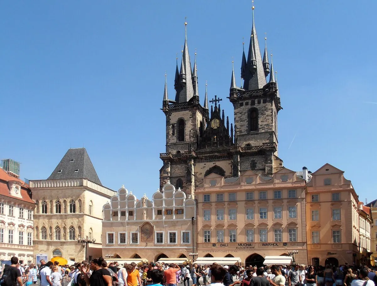 Gotyckie wieże kościoła Marii Panny przed Tynem nad kamienicami Rynku Staromiejskiego w Pradze, na placu tłum turystów