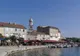Port w mieście Krk z kamiennymi domami nad wodą i wieżą dzwonnicy górującą nad zabudową