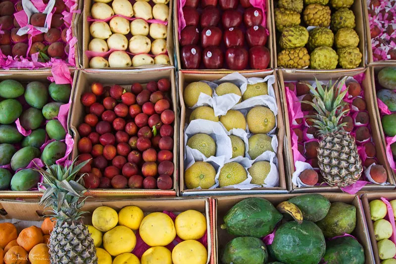 Skrzynki z mango, granatami, melonami, ananasami i innymi owocami na straganie