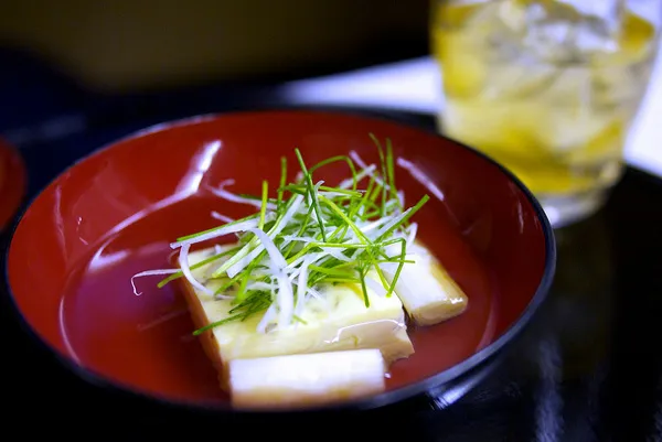 Delikatny bulion z tofu i szczypiorem w czerwonej lakowanej miseczce – danie kolacji kaiseki